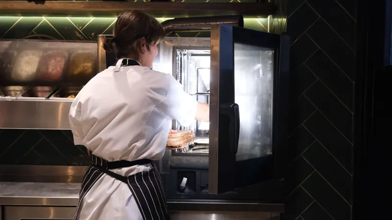 A chef working at a commercial oven in a restaurant kitchen